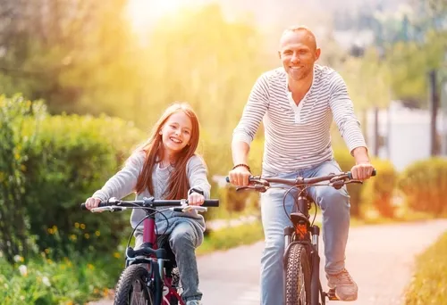 smiling father with daughter during summer outdoor bicycle riding